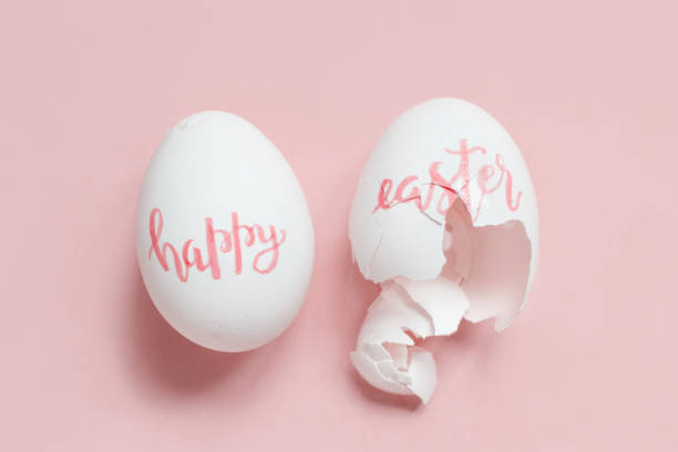 istock Broken eggs with handwritten inscription HAPPY EASTER over pink background 1216931812