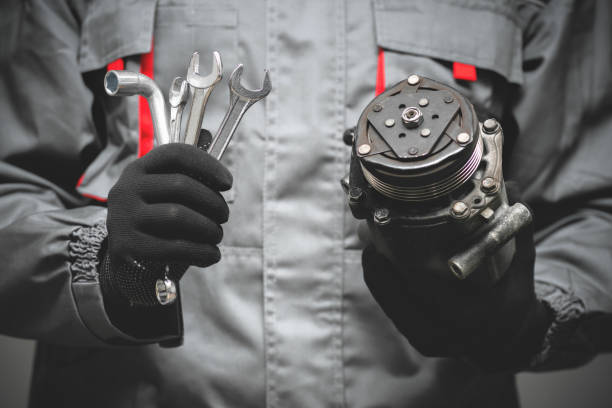 Car mechanic. Auto mechanic showing a broken air conditioning compressor close up. vehicle part stock pictures, royalty-free photos & images