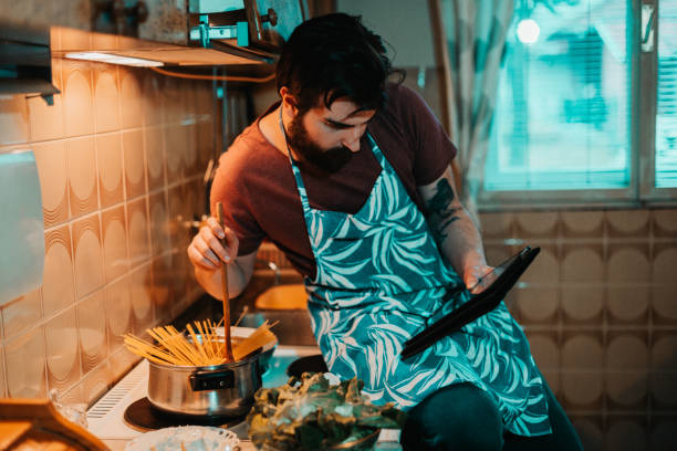 Young man reading recipe on digital tablet and cooking