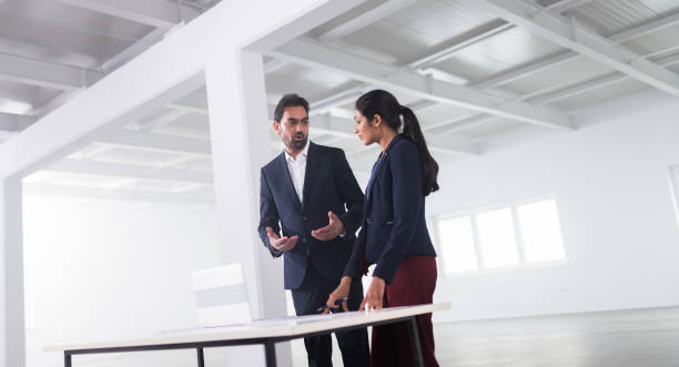istock Man And Woman Examining Plans In An Empty Office 1216938982