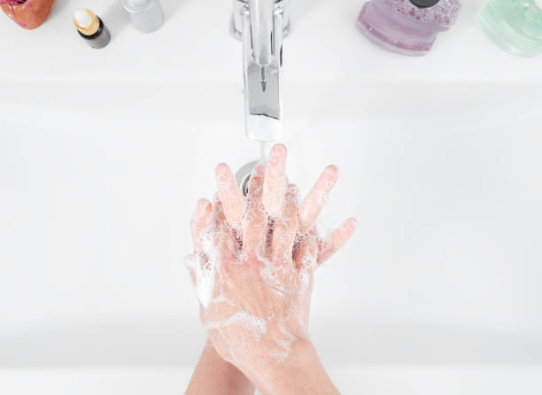 Woman use soap and washing hands under the water tap. Hygiene concept, top view, healthcare. Personal hygiene and body care stock photo