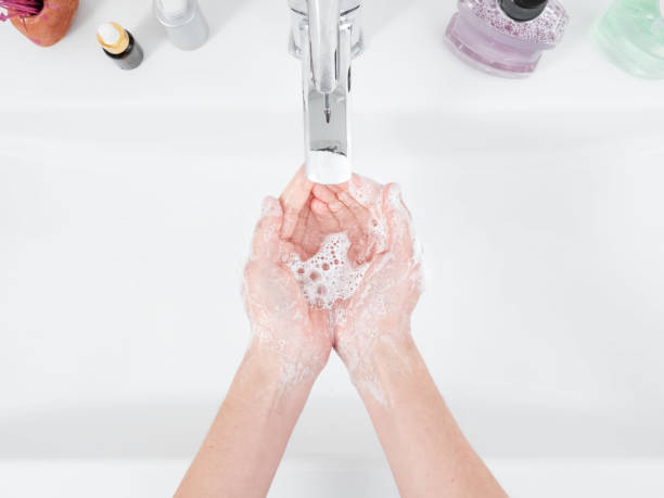 A woman washes her hands under a water tap. Hygiene concept, top view, healthcare. Personal hygiene and body care stock photo
