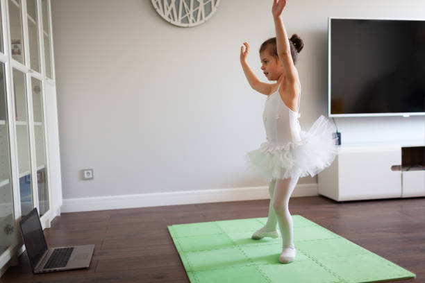 istock Pretty young ballerina practicing classic choreography during online class in ballet school, online education concept 1216940746