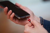Woman hands plugging a charger on a smart phone.