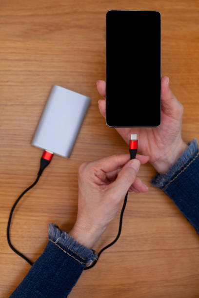 istock Woman hands plugging a charger on a smart phone. 1216940979