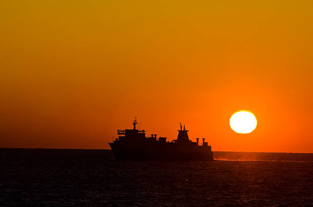 istock merchant ship underway at sunseet with big sun in background 121694167