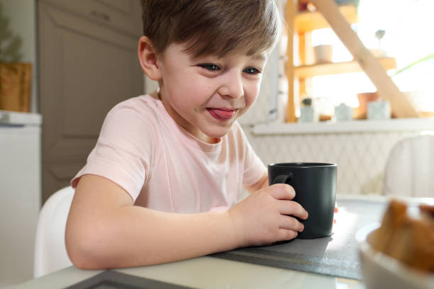 istock A little boy of 7 years in the kitchen drinks tea from a gray cup. 1216941771