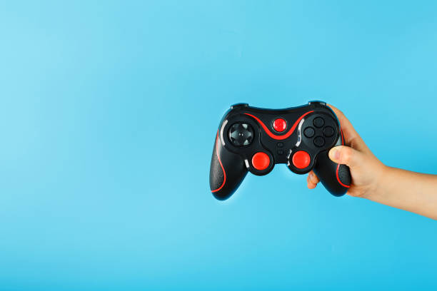 istock A child's hand triumphantly holds the gamepad on a blue background. Clear space 1216943069