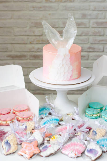 istock Mermaid theme candy bar with cake, cupcakes, macaroons and biscuits. Sea shell shaped macaroons with pearls. 1216943801