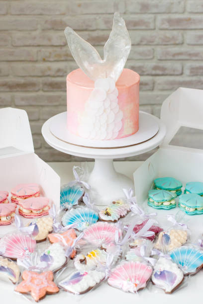 istock Mermaid theme candy bar with cake, cupcakes, macaroons and biscuits. Sea shell shaped macaroons with pearls. 1216943841