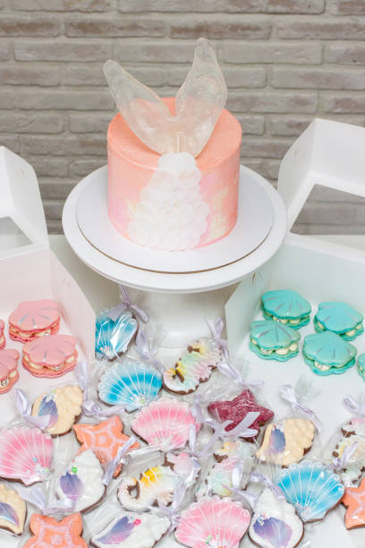istock Mermaid theme candy bar with cake, cupcakes, macaroons and biscuits. Sea shell shaped macaroons with pearls. 1216943842