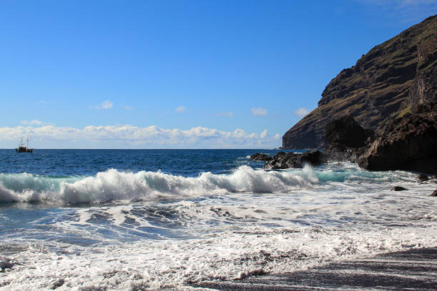 Black sand and sailing boat at the beach Playa La Veta