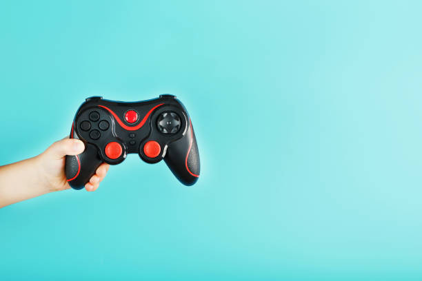 istock A child's hand triumphantly holds the gamepad on a blue background. Clear space 1216945151