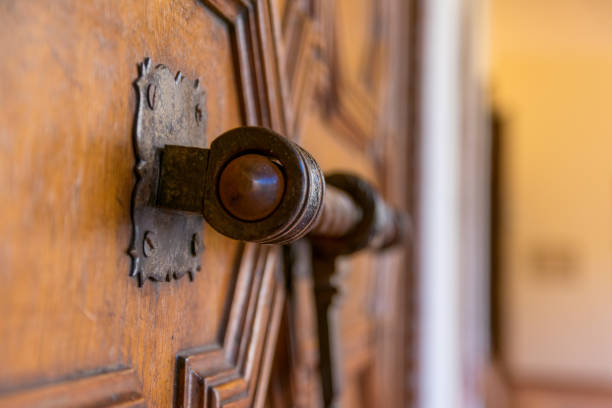 A grayscale of a snake-shaped handle on an old metal door