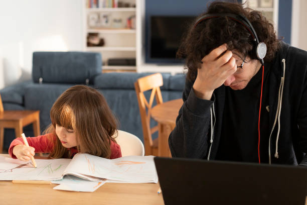 Father working at home with little daughter during covid-19 lockdown. stock photo