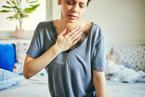 Woman having a pain in the heart area while sitting at home. stock photo