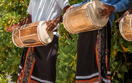 Maldivian Bodu Beru Drummers dressed in sarongs playing at the Beach. The Bodu Beru Drum is a traditional drum played at ceremonies, celebrations and festivals in Maldives