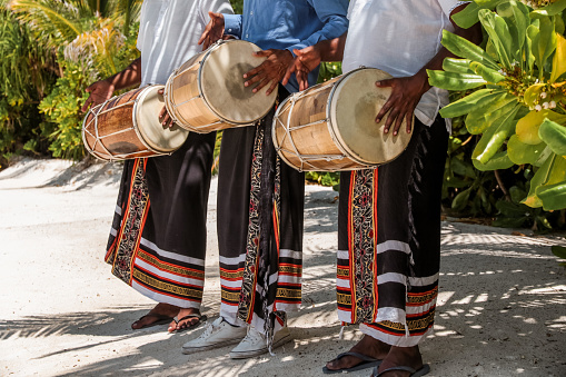 Maldivian Bodu Beru Drummers dressed in sarongs playing at the Beach. The Bodu Beru Drum is a traditional drum played at ceremonies, celebrations and festivals in Maldives