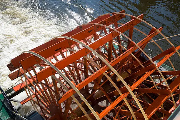 A paddlewheel on the back of a riverboat in action.