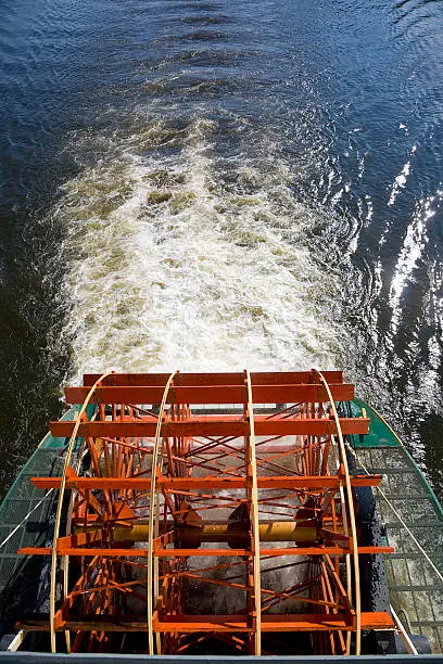 A stern paddle wheel in motion on a riverboat.