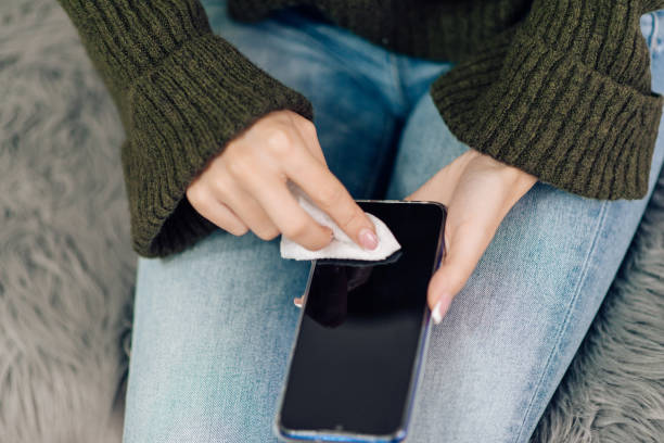 istock Young woman sanitizing her smart phone 1216953690