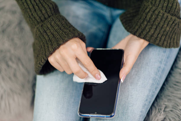 istock Young woman sanitizing her smart phone 1216953691