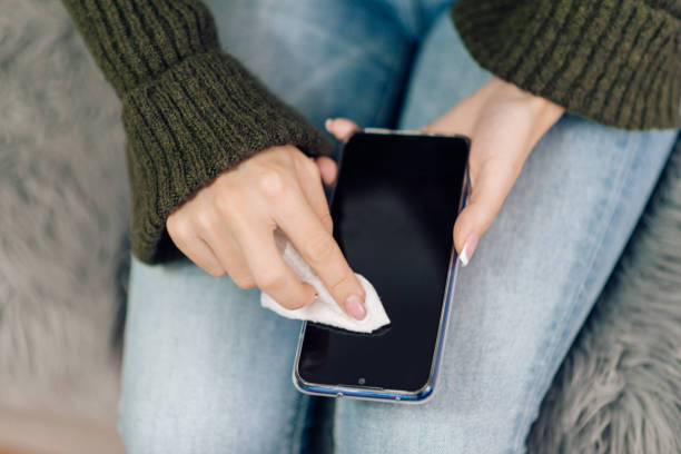istock Young woman sanitizing her smart phone 1216953753