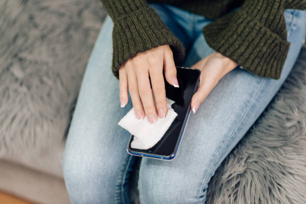 istock Young woman sanitizing her smart phone 1216953897