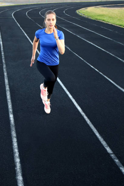 istock Runner athlete running on athletic track training her cardio in stadium. Jogging at fast pace for competition 1216954004