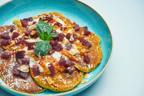 istock Appetizing pancakes with jam, sour cream and pumpkin in a blue plate isolated on grey background. Tasty breakfast food 1216955696