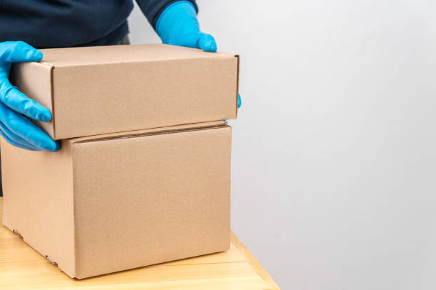 istock Contact less delivery concept, safe shipment, courier in a protective mask and rubber gloves with carboard box , order from online shop, copy space. 1216958269