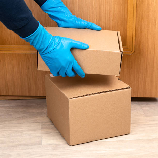 istock Contact less delivery concept, touch free shipment, courier in a protective mask and rubber gloves with carboard box , safe order from online shop 1216958303