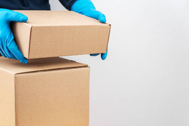 istock Contact less delivery concept, safe shipment, courier in a protective mask and rubber gloves with carboard box , order from online shop, copy space. 1216958379