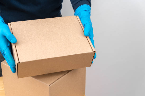 istock Contact less delivery concept, safe shipment, courier in a protective mask and rubber gloves with carboard box , order from online shop, copy space. 1216958539