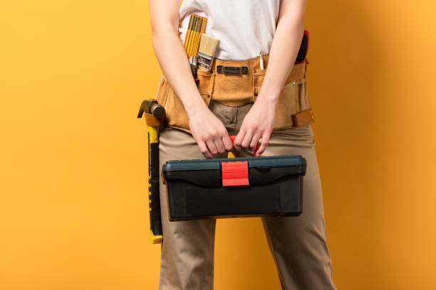 cropped view of handywoman holding toolbox on yellow background cropped view of handywoman holding toolbox on yellow background woman wearing tool belt stock pictures, royalty-free photos & images