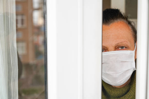 istock old woman looking out the window. 1216963126