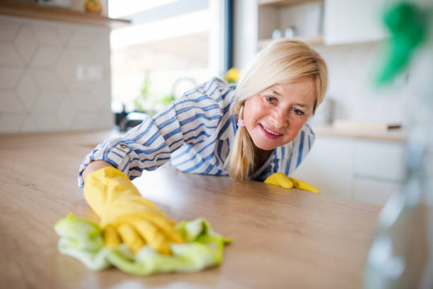 retrato de la mujer mayor limpiando mostrador de cocina en el interior en casa. - cleaning domestic kitchen counter top housework fotografías e imágenes de stock