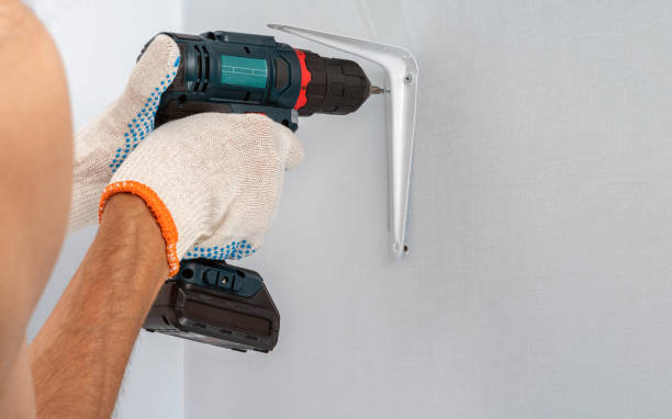 istock A worker fastens the bracket to the wall with a cordless screwdriver. 1216964087