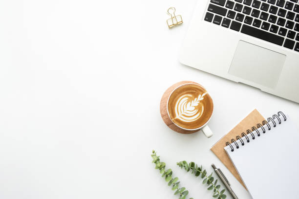 istock White office desk table with blank notebook, pen, laptop computer, cup of latte coffee and supplies. Top view with copy space, flat lay. 1216964635