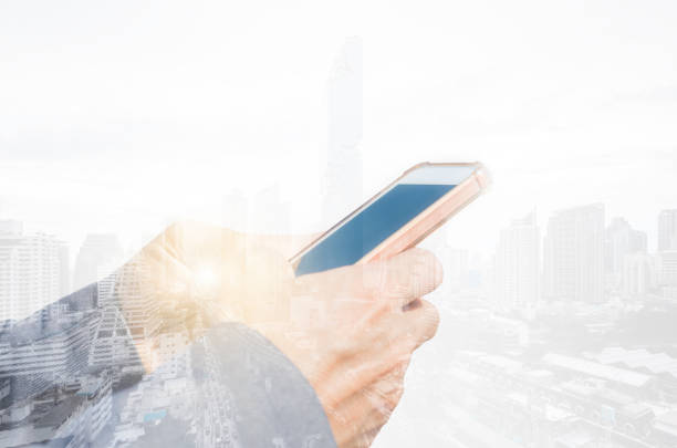 istock double exposure business man hands use smartphone typing on screen for working with technology wireless communication connection with cityscape building background. 1216968188