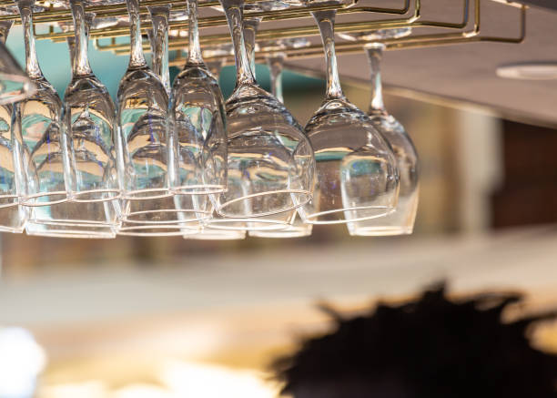 istock Glasses hanging from a bar with a bartender serving guests in the blurred background. 1216968539