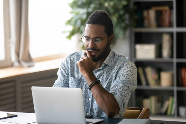 istock Smiling handsome young african american guy looking at computer screen. 1216968855
