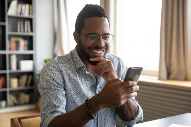 istock Smiling millennial biracial guy reading pleasant good news sms. 1216968888