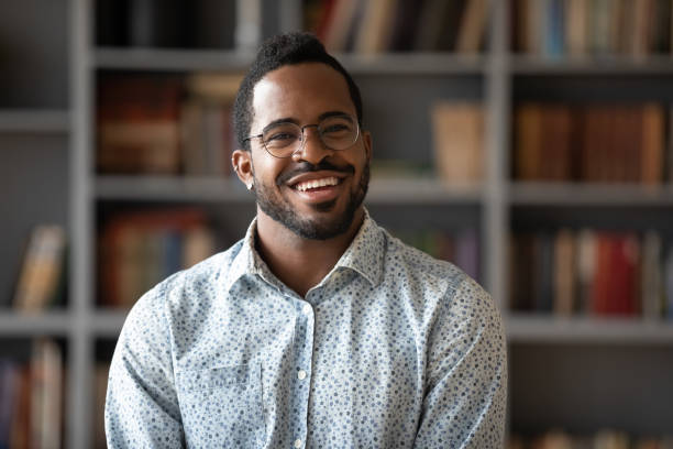 Head shot portrait of happy young african american businessman. Happy young african american businessman entrepreneur in glasses, head shot portrait. Smiling millennial biracial man in eyewear looking at camera, posing for photo in modern office, library or home. salesman photos stock pictures, royalty-free photos & images