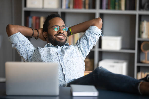 istock Relaxed happy young african american man put legs on table. 1216969440