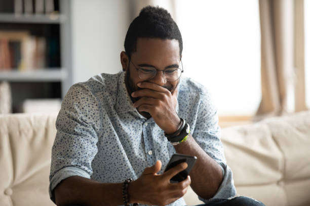 istock Funny young african ethnicity guy looking at cellphone screen. 1216969486