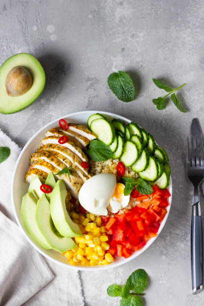 istock Buddha bowl with soft boiled egg, avocado, grilled chicken, cucumber, bell pepper, corn and bulgur. Concept for clean and balanced healthy food. Top view. 1216969895