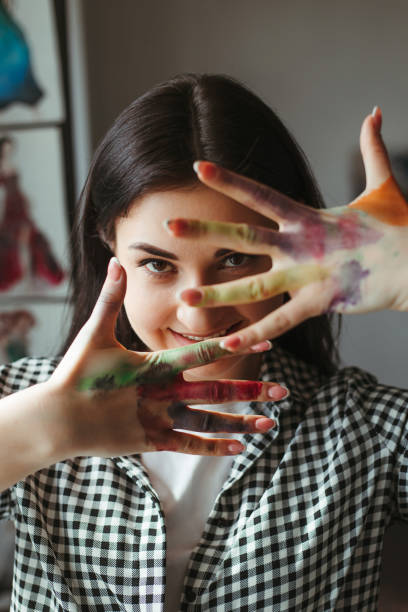 istock Young talented woman showing hands dirty in paint 1216970193