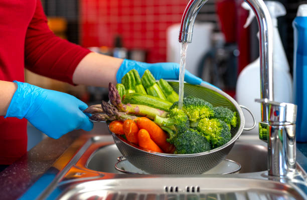 Woman washing vegetables on kitchen counter.