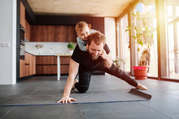 istock Father working out, doing single arm plank with his jolly baby riding on him 1216971790